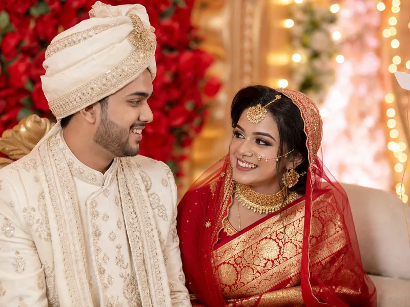 Bangladeshi Muslim wedding couple in Dhaka - bride in red benarasi saree and groom in ivory sherwani on decorated wedding stage - Anika and Farhan's success story